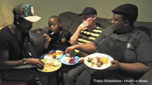 Zanele Malambe (far right) and her 9-year-old son Tshepo sit down to a Sunday dinner of pap, potato salad, pumpkin, beetroot, and a tinned fish and macaroni salad.